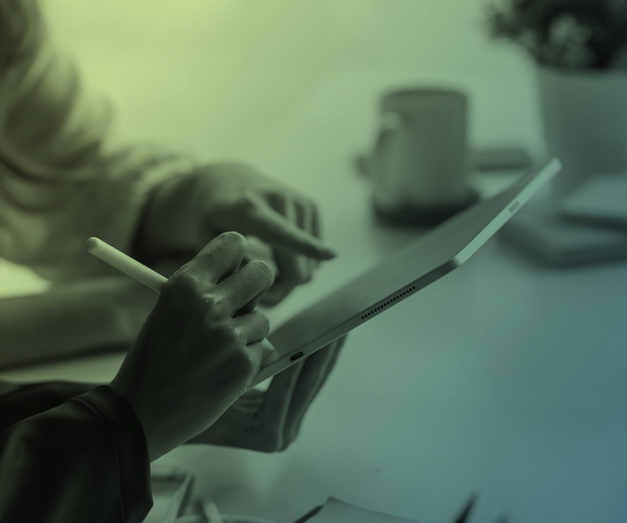 Close up of hands holding a pen and pointing at a tablet screen.