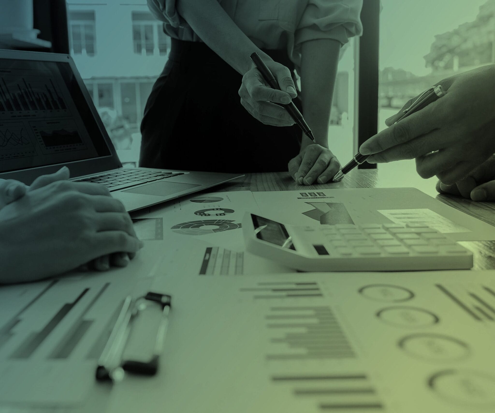 People around a table with a laptop, calculator and documents.
