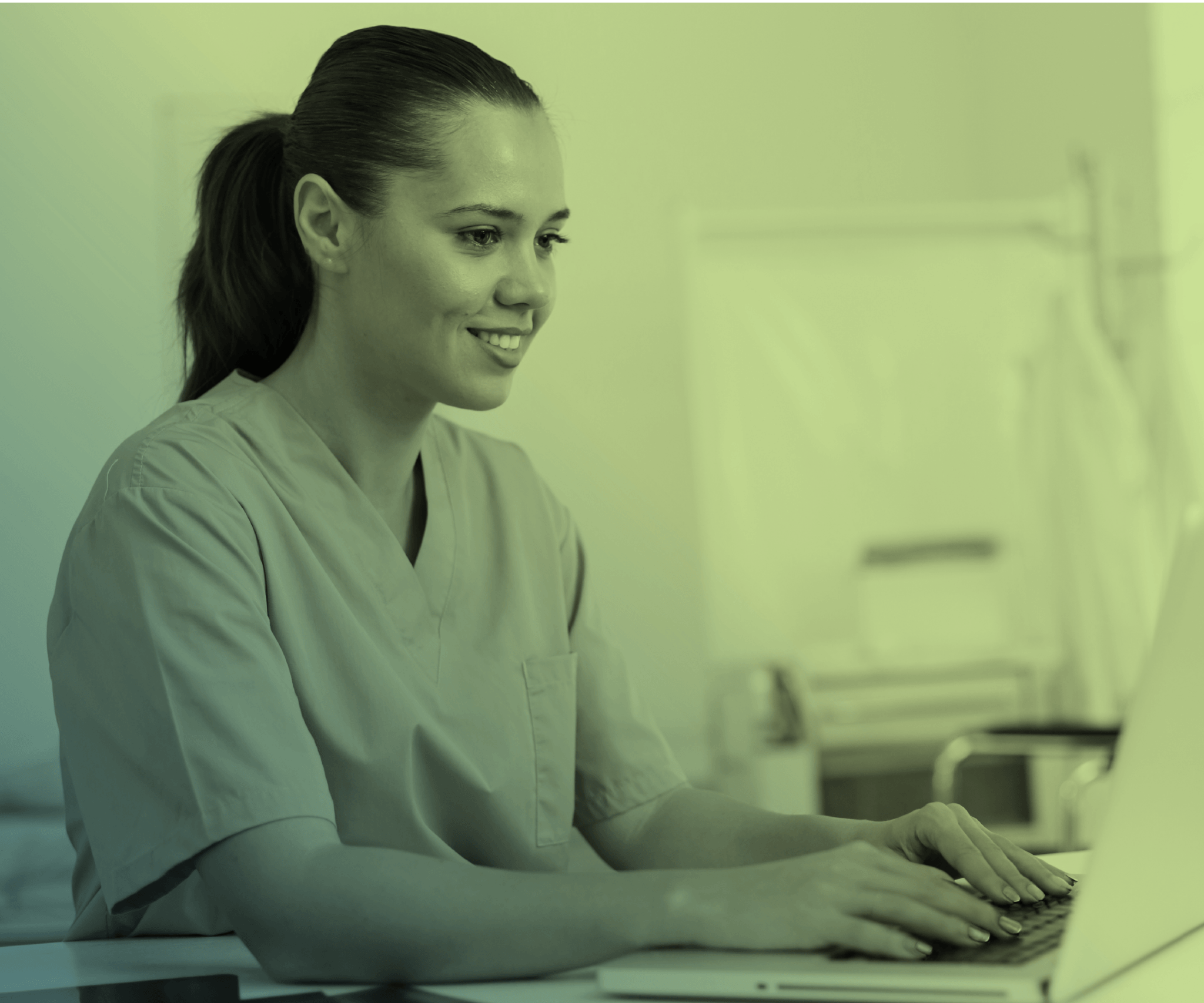 A dental assistant in scrubs looking at a laptop.